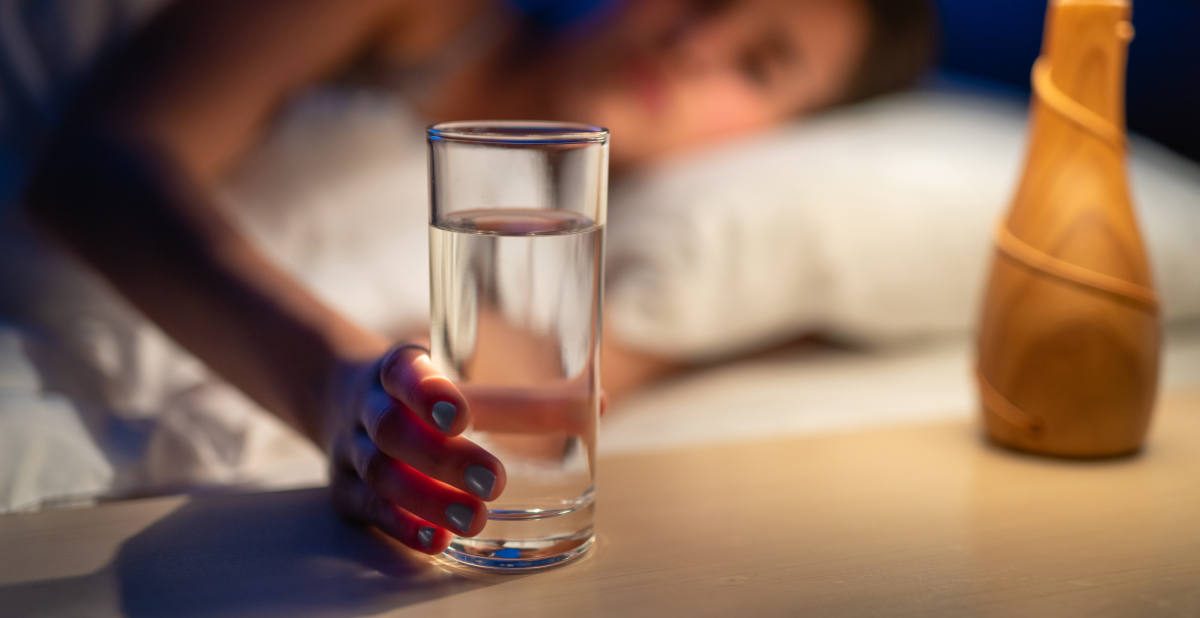 Woman reaching for water in bed